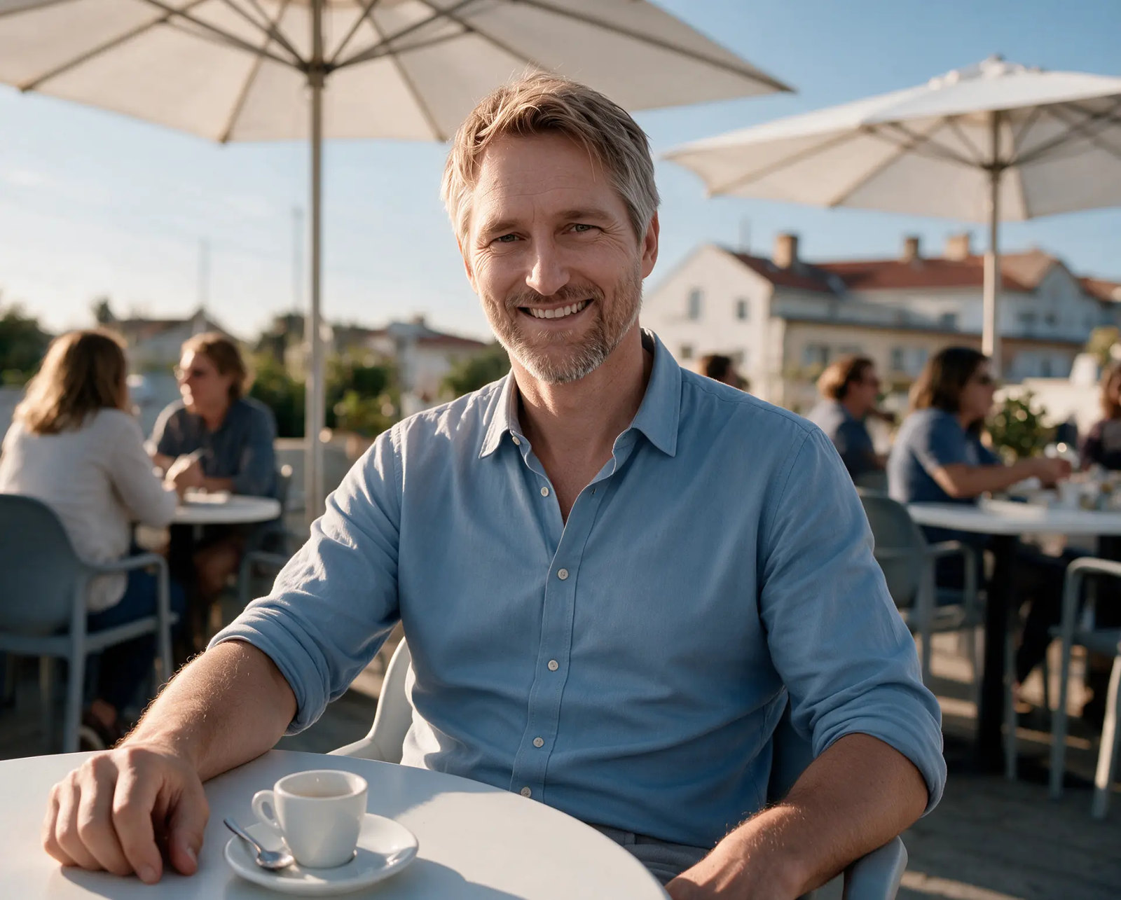 Alexander Brink, Online-Marketer seit 2018, im hellblauen Hemd in einem sonnigen Straßencafé